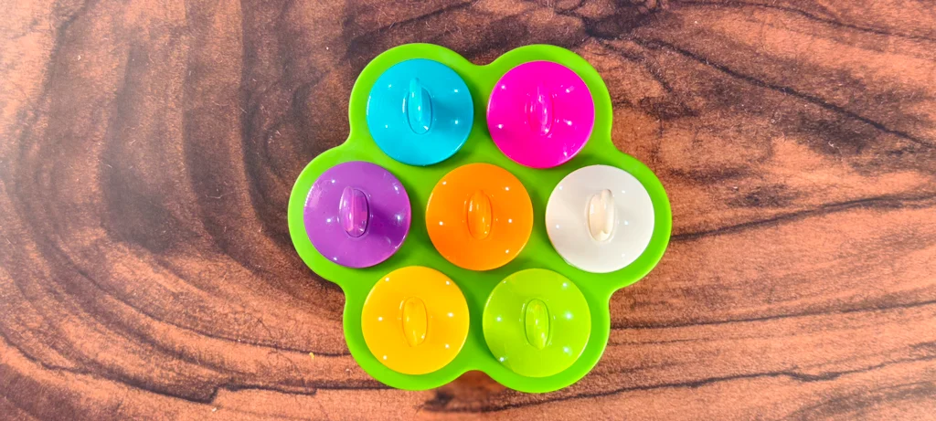 A silicone popsicle mold with popsicle handles inserted into the mango coconut puree.