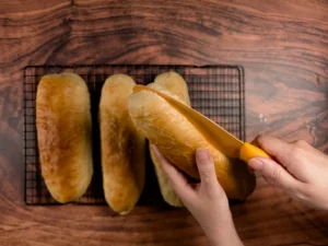 Slicing sub sandwich rolls.