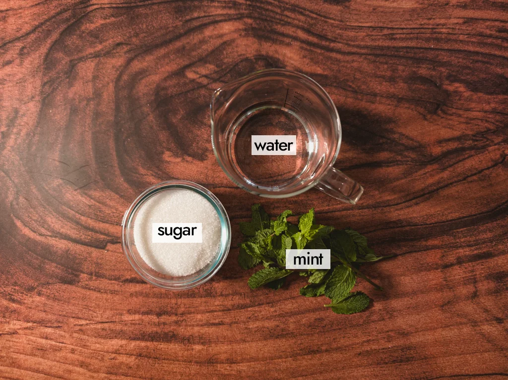 A glass of sugar, a glass of water, and some sprigs of mint.