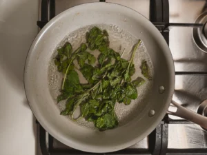 Medium saucepan with boiling sugar water and mint sprigs.