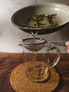 Straining mint simple syrup into a glass.