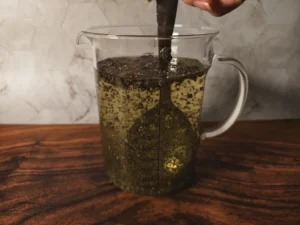 A spoon stirring a glass of coconut water and chia seeds.